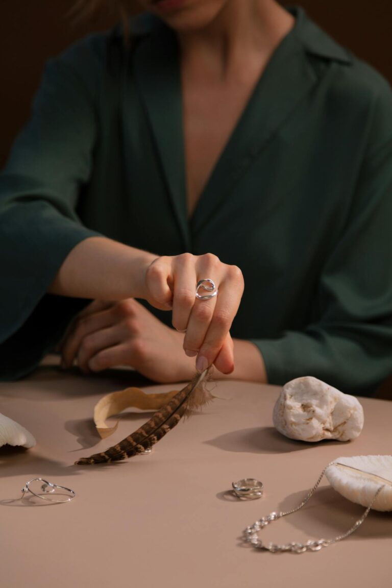 A close-up of a woman in green showcasing silver jewelry with feather and stone accents.