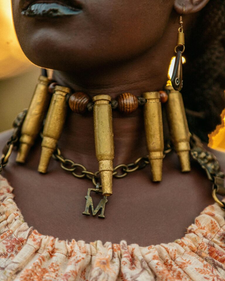 Close-up portrait of a woman with a unique bullet and chain necklace and stylish earrings.